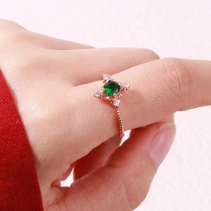 Close-up of rose gold branch ring featuring a green gemstone on a model hand