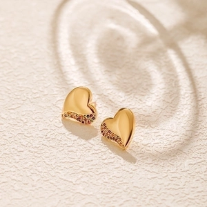 Polished heart stud earrings with colorful zircon stones on white textured surface