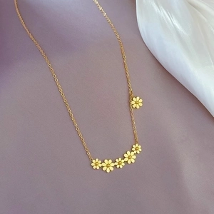 Detailed shot of golden daisy flower pendants on a delicate titanium steel chain