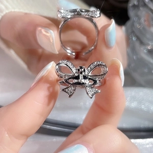 Silver bow knot ring with Saturn charm and sparkling crystals in adjustable open design