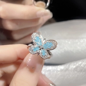 Silver butterfly open ring with blue enamel and white crystals held in hand