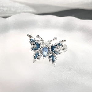 Macro view of silver butterfly ring featuring blue enamel wings and a marquise gemstone