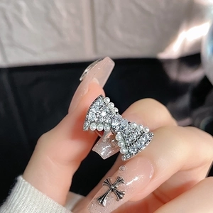 Detail of silver butterfly ring with pavé crystals, heart diamond, and pearls on finger