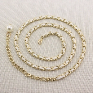Detail of golden metal chain belt with white leather weave and large pearl pendant charm