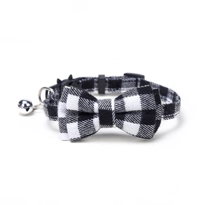 Detail of British plaid bow pet collar with silver bell and fabric texture display