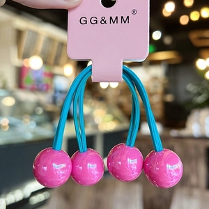 Close-up of four pink spherical hair ties with blue elastic bands on a branded card