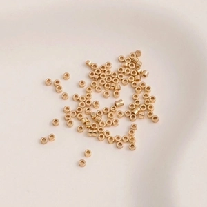 14K gold plated cylindrical spacer beads for DIY jewelry making on beige ceramic