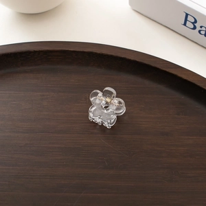 Close-up of mini transparent flower hair claw clip on a wooden display tray