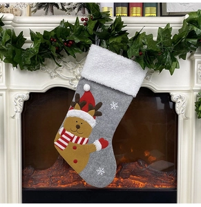 Detail of grey felt Christmas stocking with reindeer pattern hanging on a festive mantel