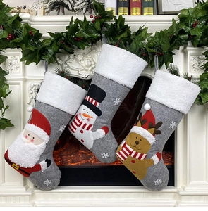 Three grey felt Christmas stockings with Santa, snowman, and reindeer hanging on a fireplace