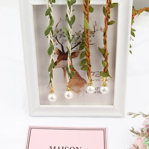Detailed close-up of woven cotton waist ropes with green leaf tassels and white pearl charms