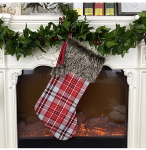 Detail of red plaid Christmas stocking with faux fur cuff hanging on a festive mantel
