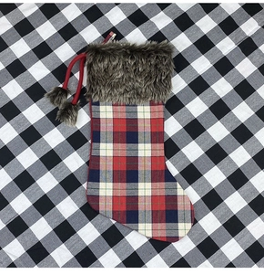 Detail of plaid Christmas stocking with faux fur cuff and pom pom hanging strings