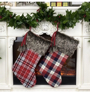 Plush Christmas stockings in red and blue plaid hanging on a cozy fireplace mantel