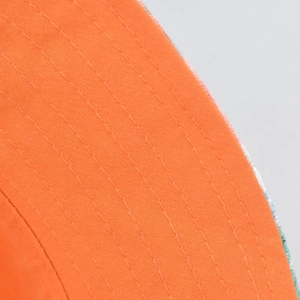 Detailed close-up of orange canvas sun hat brim with reinforced stitching and floral lining