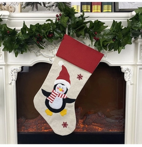 Close-up of a burlap Christmas stocking with a cartoon penguin hung on a cozy fireplace