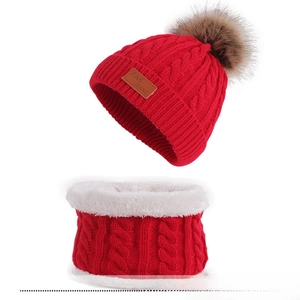 Detail of red cable-knit winter set featuring thick faux fur lining and pompom beanie
