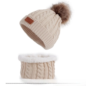 Detail of beige knitted baby hat and neck warmer set with faux fur lining and pompom