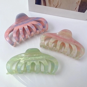 Detailed view of large gradient acetate hair claws in pastel purple, pink, and yellow hues