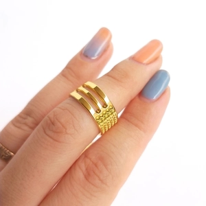 Vue détaillée d'une bague multicouche dorée ajourée avec des accents de texture perlée