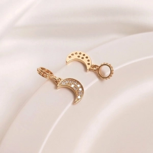 Macro shot of 14K gold plated crescent moon pendants with micro-set zircon and bead details