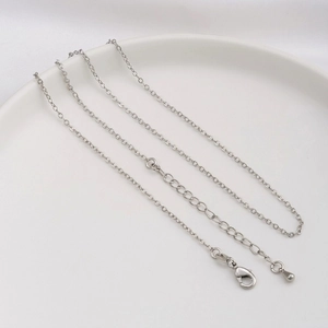 Detailed macro view of a silver flat O-chain necklace with a lobster clasp and waterdrop charm
