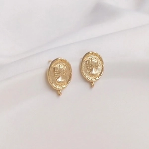 Vintage 14K gold plated oval queen cameo earrings on soft white fabric background