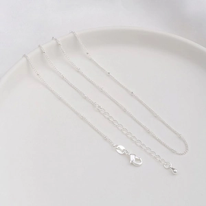 Detailed view of silver bead chain necklace with lobster clasp and teardrop extension