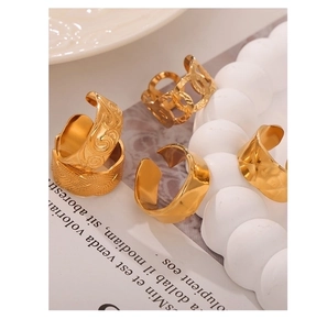 Close-up of golden open rings featuring smooth, embossed, and chain textures on props