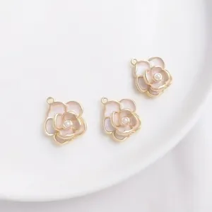 Detailed macro view of 14K gold camellia flower pendants with pink petals and small pearls