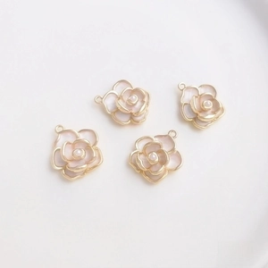 Detailed macro view of four 14K gold-plated camellia pendants with pearls for DIY jewelry