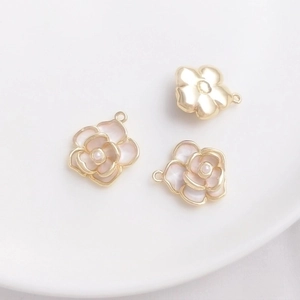 Detailed view of three 14K gold-plated camellia flower pendants with white enamel and pearls