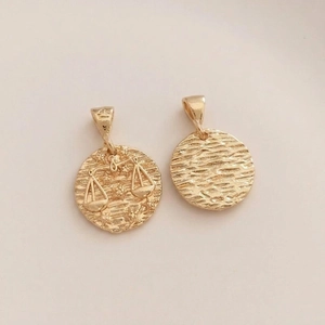 Macro view of 14K gold plated Libra zodiac pendant with textured finish and star pattern