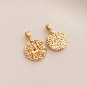Macro shot of 14K gold-filled Sagittarius zodiac coin pendant with detailed starry engravings