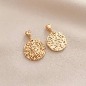 Macro detail of 14K gold-plated Aquarius zodiac charm showing embossed design and ripple texture