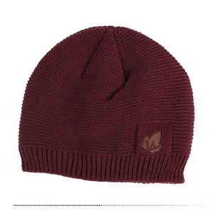 Detail of burgundy knit beanie featuring a dark brown leather maple leaf patch texture