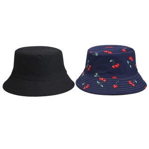 Close-up detail of a cotton sun hat showing navy blue fabric with cherry print patterns