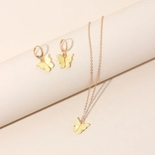Close-up of golden butterfly necklace and earrings set on minimalist jewelry stands