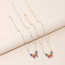 Detail of gold and silver butterfly necklaces with colorful crystal enamel pendants