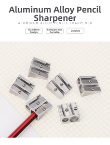Detailed macro view of silver aluminum alloy dual-hole pencil sharpener on grid paper