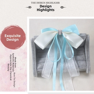 Detail of light blue and white bow hair clip with pearls and long flowing ribbons
