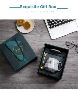 Detail showing a marble ceramic mug with a gold leaf spoon in a premium green gift box