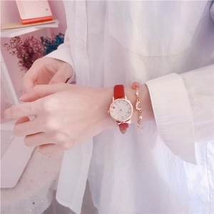 Close-up of women's red leather watch set with rose gold moon and star charm bracelet
