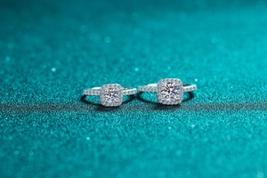 Macro view of 1 carat moissanite rings with square halo on green glitter background