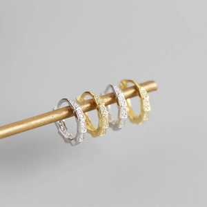 Dettaglio di orecchini a cerchio geometrici a bambù con pavé di zirconi e finitura