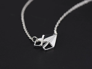 Vue rapprochée du pendentif avion en papier argenté sur surface noire