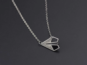 Vue détaillée du pendentif avion en papier argenté sur une fine chaîne en acier titane