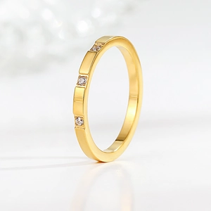 Close-up of a minimalist gold titanium steel ring featuring three sparkling inset diamonds