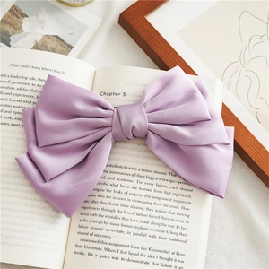 Detail of lavender satin layered bow hair clip on a vintage book background