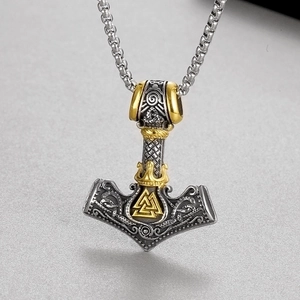 Macro view of Viking Mjolnir pendant with golden Valknut symbol on a steel chain